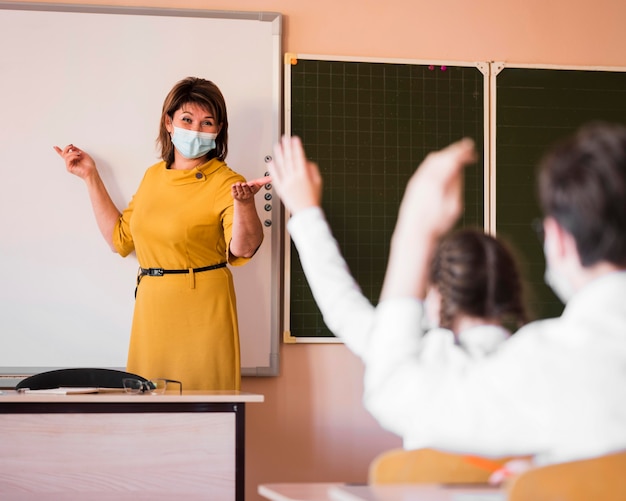 Foto gratuita studenti e insegnanti con maschera in classe