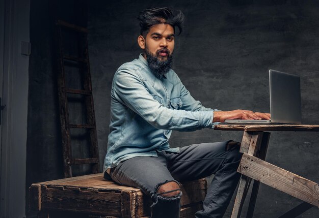 Stylish bearded Indian male working with laptop.