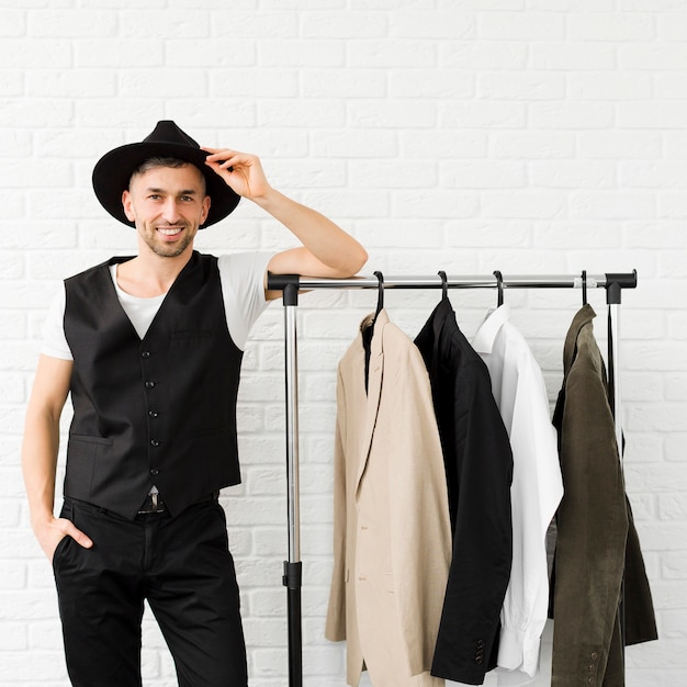 Free Photo stylish man wearing a hat and standing next to wardrobe