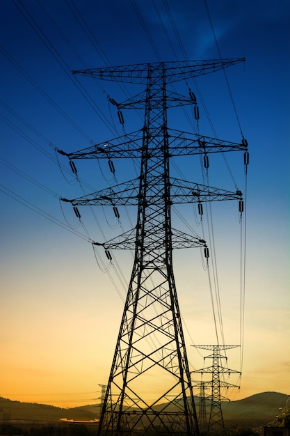 Free Photo sun setting behind the silhouette of electricity pylons