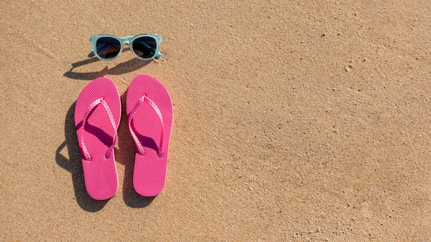 Free photo sunglasses and beach slippers on sand