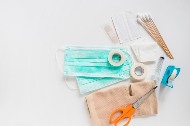 Free photo surgical mask; bandage; gauze; cotton swabs; sticky bandage and knee brace with scissor on white background