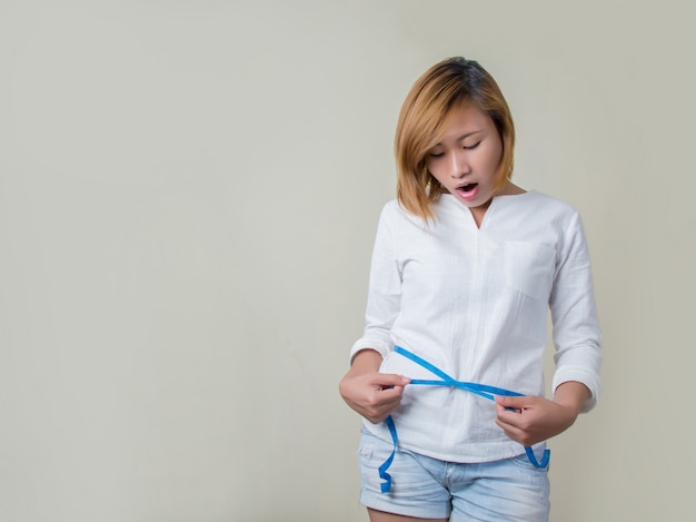 Free Photo surprised woman measuring her waist