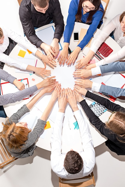 Free Photo team sitting behind desk, checking reports, talking and connecting hands together. top view. business concept of collaboration, team work, meeting