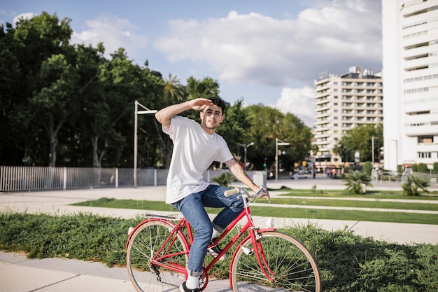 Free photo teenage cyclist riding bike and shielding eyes