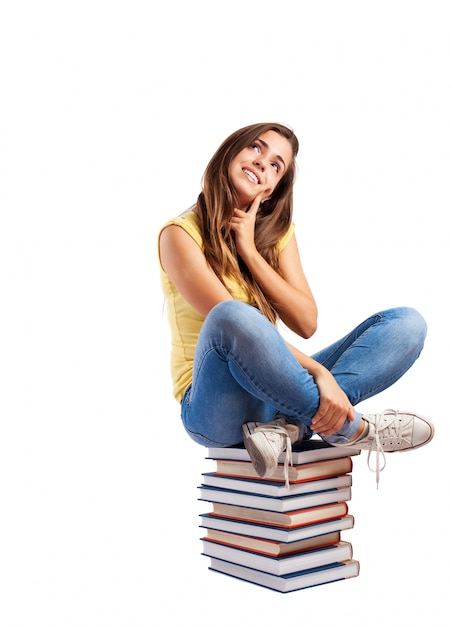 Thoughtful girl sitting on books