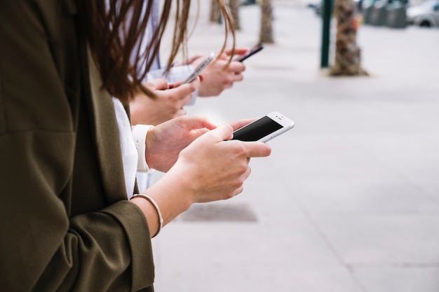 Free Photo three people using cell phone outdoors