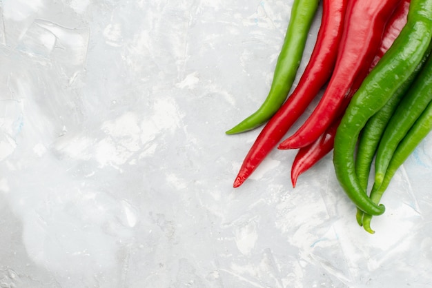 Free Photo top view colored spicy peppers green and red on grey desk