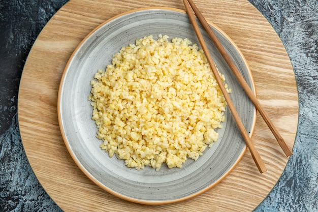 Foto gratuita vista dall'alto di orzo perlato cotto con bastoncini sulla superficie chiara