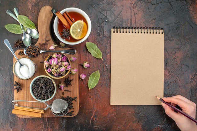 Top view cup of tea with black tea and dried flowers on the dark brown background tea water color breakfast photo drink ceremony biscuit