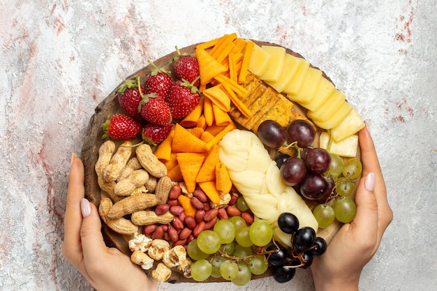 Free photo top view of different delicious snacks fresh grapes cips cheese and nuts on the white surface