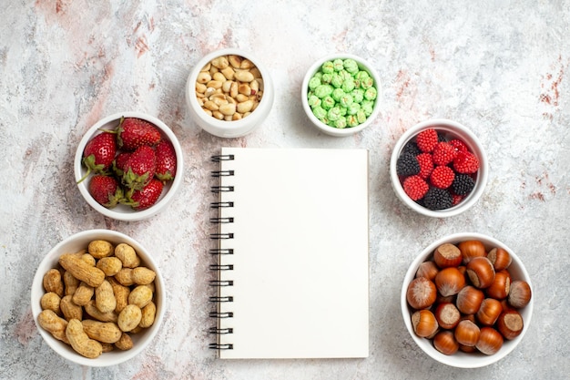 Free photo top view of different snacks peanuts hazelnuts and candies on white surface