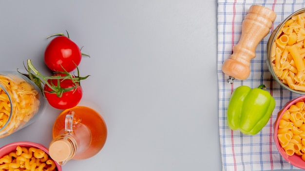 Free Photo top view of different types of pasta as cavatappi pipe-rigate and others with tomato butter pepper salt on plaid cloth and blue surface with copy space