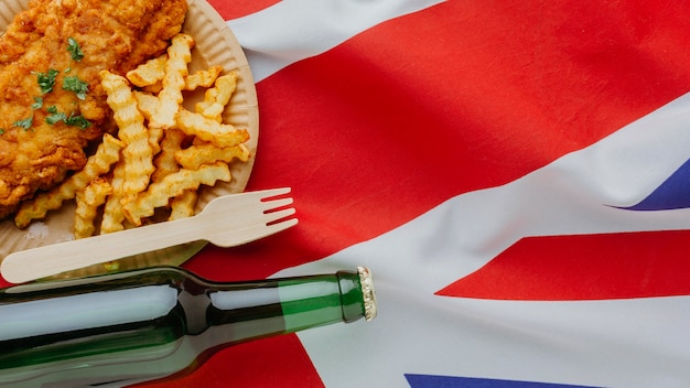 Free photo top view of fish and chips on plate with beer bottle and great britain flag