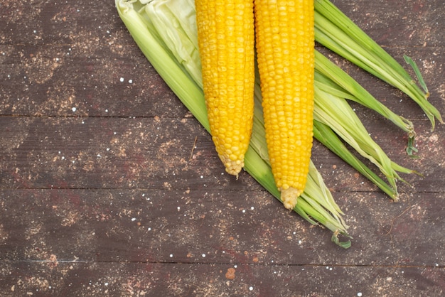 Top view fresh yellow corns with peels on brown food