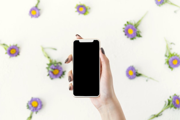 Free Photo top view hand holding a phone surrounded by flowers