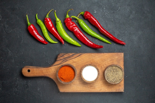 Free Photo top view horizontal row green and red peppers different spices on cutting board on dark surface