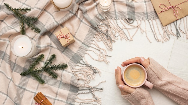 Free photo top view of person holding mug with candles and blanket