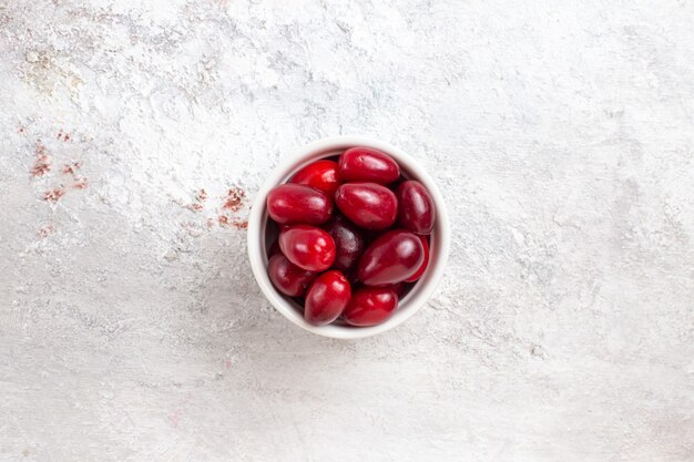 Top view red dogwoods inside little plate on white surface berry fruit color tree plant