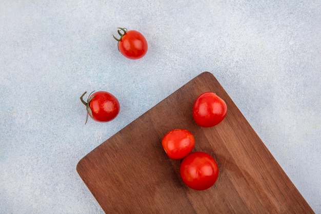 Free Photo top view of red fresh and cherry tomatoes on a wooden kitchen board on white surface