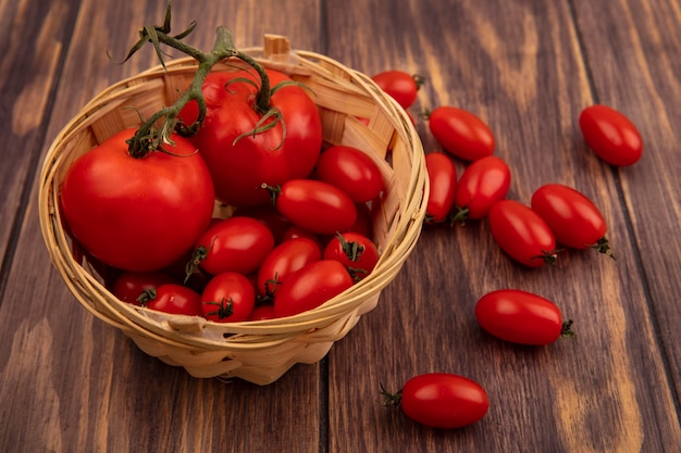 Free photo top view of red fresh tomatoes on a bucket on a wooden wall