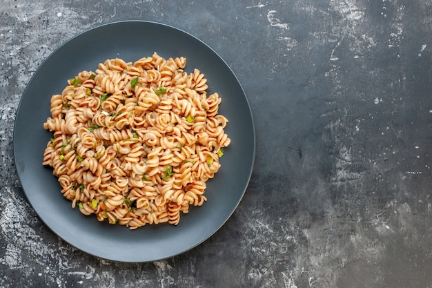 Foto gratuita pasta rotini vista dall'alto su piatto rotondo su superficie scura con spazio libero