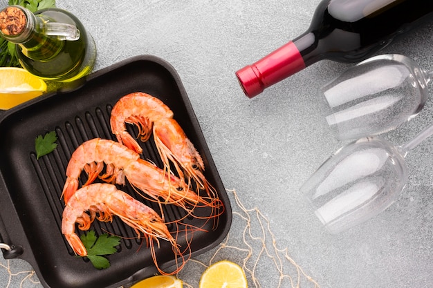 Free photo top view shrimp in pan with wine bottle