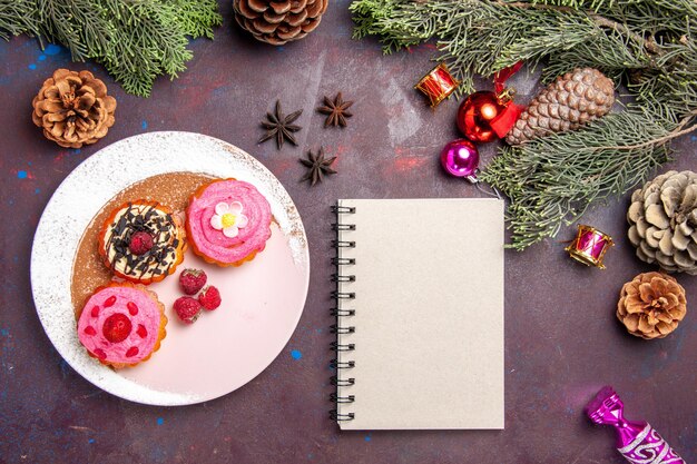 Top view of sweet delicious cakes with cream and fruits on black