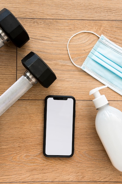 Top view of weights with hand sanitizer and smartphone