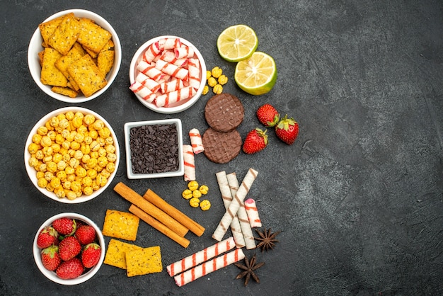 Free photo top view yummy snacks with crackers pieces of chocalate slices of lemon on the black background with free space