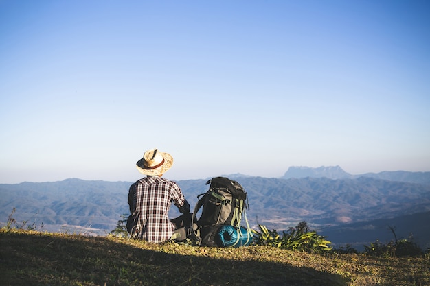 Foto gratuita turista dalla cima della montagna. i raggi del sole. l'uomo indossa un grande zaino contro la luce del sole