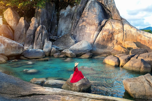 Tourist sitting on the rock near Grandfather and grandfather rock Hin Ta and Hin Yai Rocks on the Lamai Beach Koh Samui Thailand