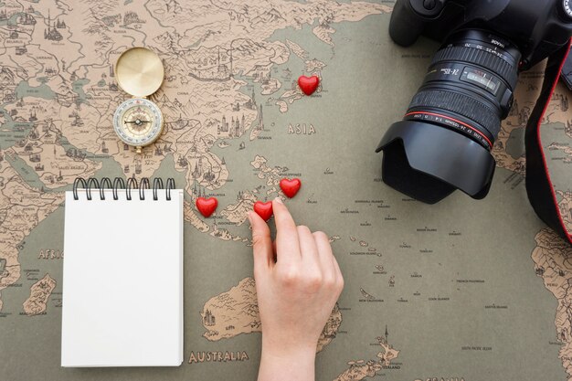 Travel background with hand placing hearts on a world map