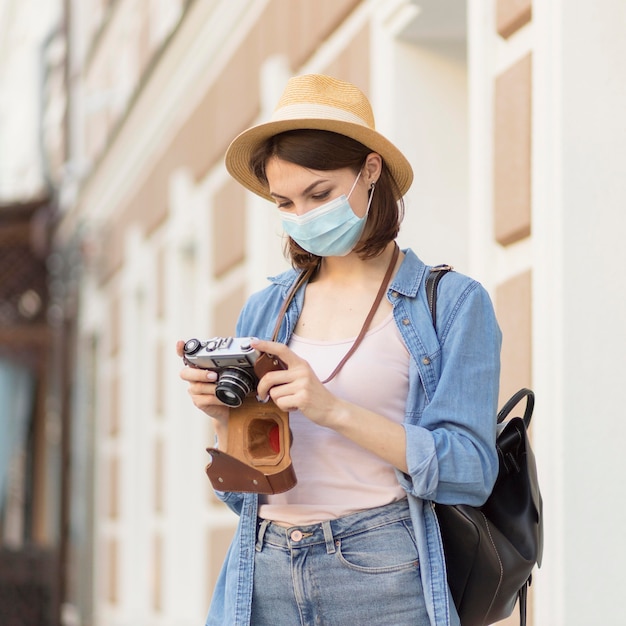 無料Photo 帽子と医療マスクの写真をチェックする旅行者