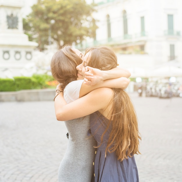 Free photo two female friends hugging each other at outdoors