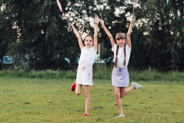 Free photo two girls enjoying in the park holding badminton