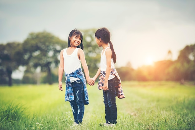 Foto gratuita una mano di due bambine che tiene insieme divertendosi nel parco