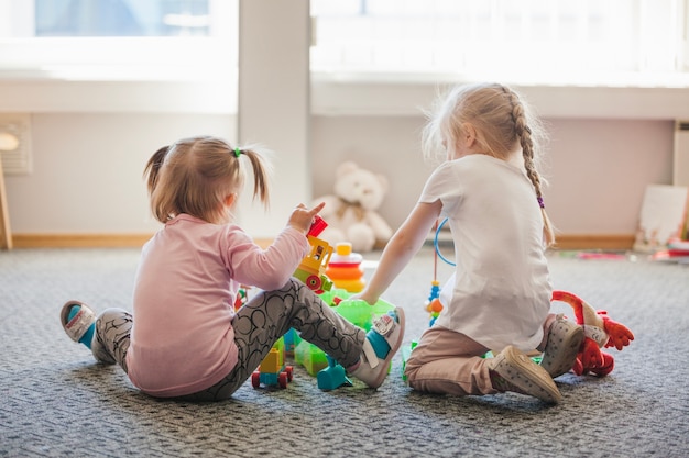 Free photo two little girls sitting on floor playing