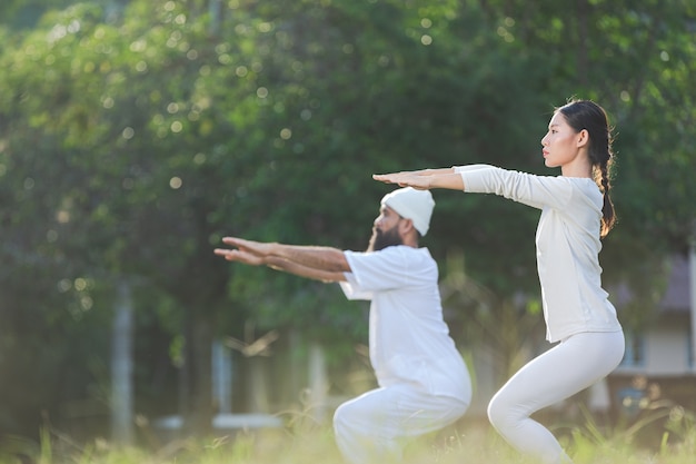 Free Photo two people in white outfit doing yoga in nature