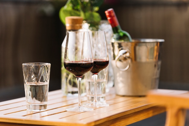 Free photo two red wine glasses and glass of water on wooden table