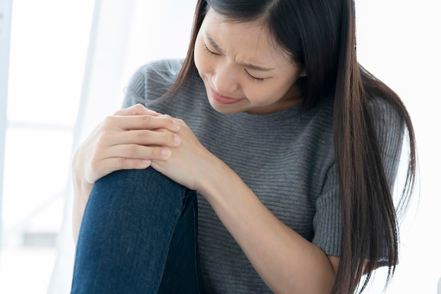 Free photo unhappy asian woman touch leg knee with hurt and injure white background