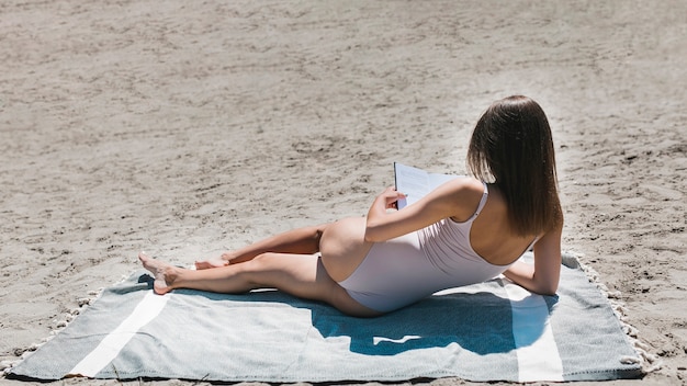 Free Photo unrecognizable woman reading on beach