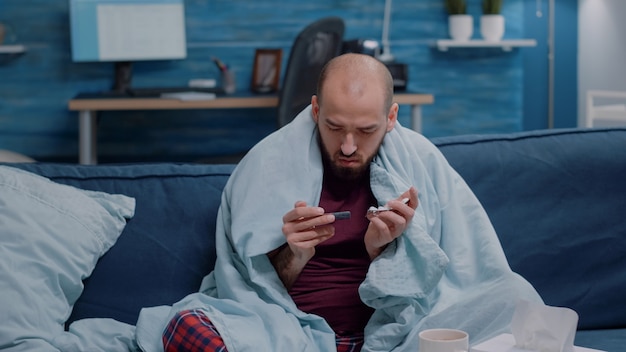 Free Photo unwell man holding tablets with capsules in hand