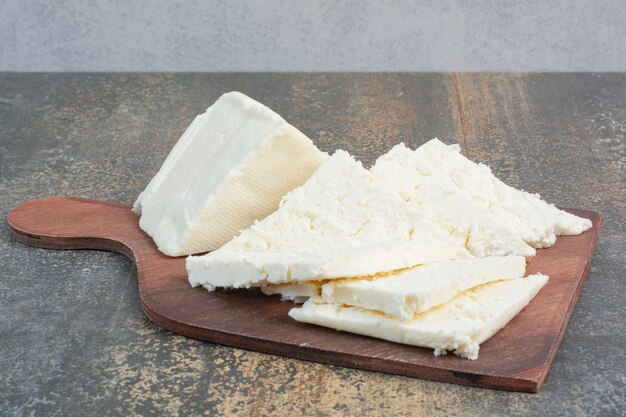 Various white cheese on wooden board.