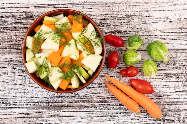 vegetable salad with carrot and radish in a ceramic bowl on white wooden table