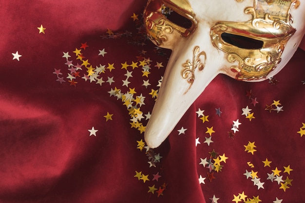 Free photo venetian mask with a long nose and star confetti