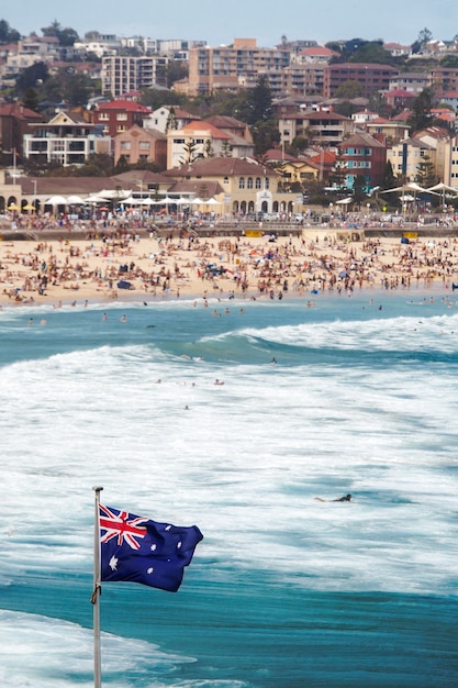 Free photo vertical shot of the australian flag at the sea in a crowded bondi beach