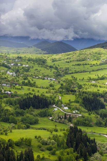 Free photo vertical shot of a beautiful village on the grass covered hills