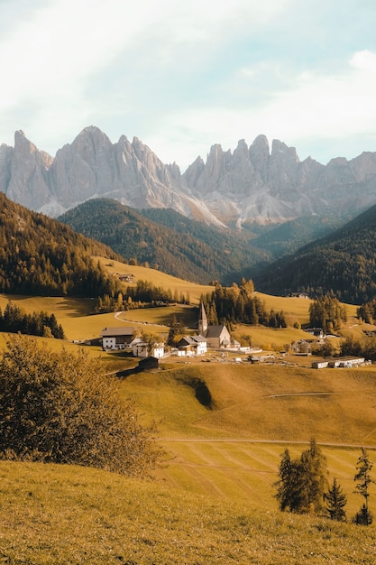 Foto gratuita scatto verticale di un bellissimo villaggio su una collina circondata dalle montagne