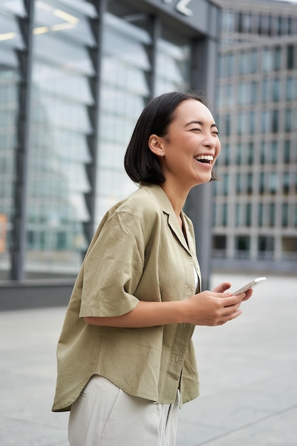 無料写真 通りを歩いて笑って、一日を楽しんで幸せそうに見える美しいアジアの女性の垂直ショット